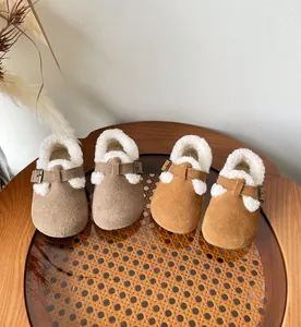Cozy fleece-lined children's clogs in tan and taupe on a wooden rattan table