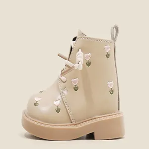 Detailed side view of beige baby girl Martin boots featuring pink heart embroidery