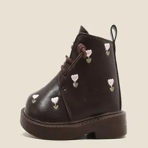 Detail of toddler girl's brown leather boots with pink flower embroidery and laces.