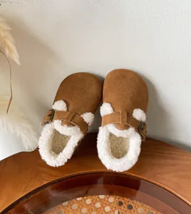 Cozy brown suede children's clogs with thick white fleece lining and buckle detail.