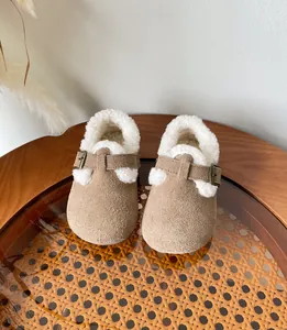 Cozy children's winter clogs with warm white fleece lining and brown suede finish on table