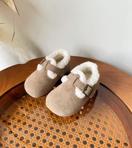Detail view of cozy children's suede clogs with soft white fur lining and buckle.