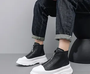 Detail view of men's trendy black leather boots with thick white sole and front zipper
