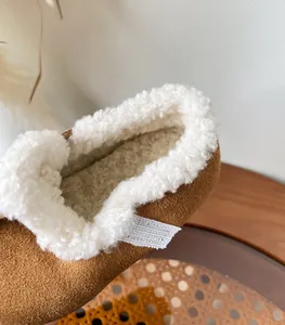 Close-up detail of soft white fleece lining inside brown suede children's winter shoes