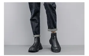 Close-up view of men's black leather platform ankle boots with front zipper detail
