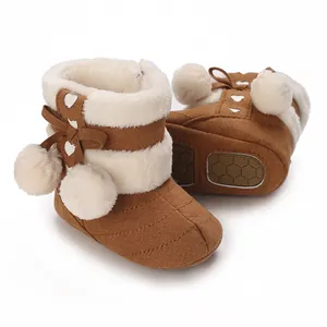 Detailed view of brown baby winter snow boots with plush white fur and soft pom-poms