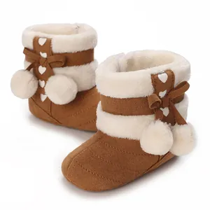 Detail view of brown baby winter boots with soft white fur lining and cute pom-poms