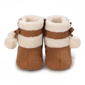 Detailed view of warm brown baby winter boots with white faux fur and pom-pom detail