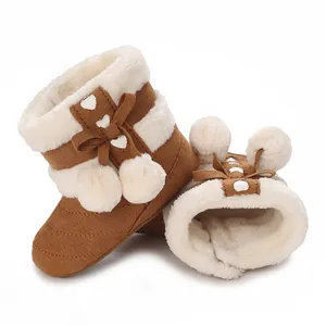 Soft brown suede baby boots with thick white faux fur lining and pom-pom detail