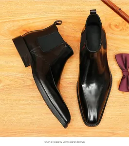 Detalle de botines Chelsea de cuero negro para hombre con punta fina y grabado sutil