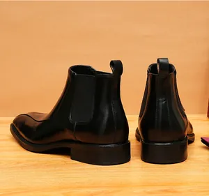Vista lateral y trasera de botas Chelsea de cuero negro con un elegante grabado decorativo