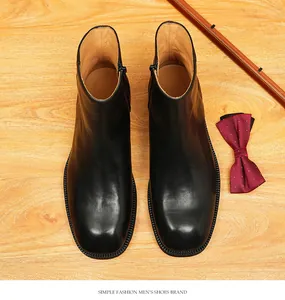 Detailed top-down view of black square-toe leather Chelsea boots on a stylish wood surface