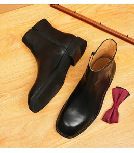 Close-up of premium black leather Chelsea boots featuring a square toe and side zipper.