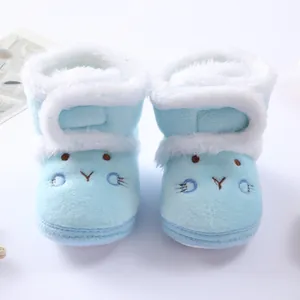 Macro view of light blue soft fleece baby boots featuring a cute cartoon face embroidery