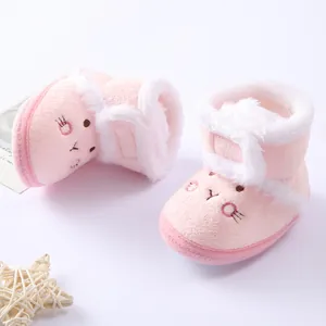 Close-up of pink plush baby boots with cute cartoon embroidery and white faux fur trim.