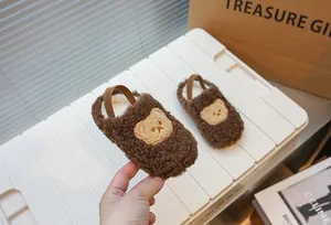 Vista dettagliata delle scarpine primi passi in peluche marrone con motivo a orso
