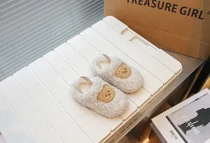 Primo piano di accoglienti pantofole di peluche per neonati con orsetto ricamato