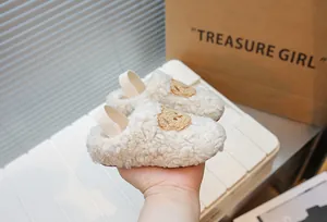 Dettaglio macro di scarpe da camminata per neonati in peluche bianco con ricamo orso