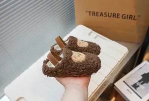 Dettaglio ravvicinato di pantofole per neonati in peluche marrone con motivo a orso