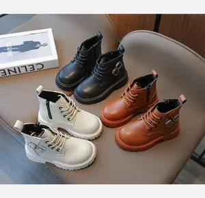 Bottes Martin pour enfants en noir, beige et marron présentées sur une chaise moderne.