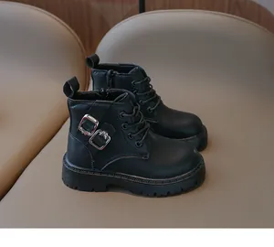 Détail rapproché des bottes Martin en cuir noir pour enfants avec boucles argentées.
