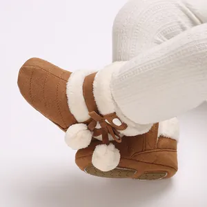 Close-up detail of brown baby winter boots with soft white faux fur trim and pom-poms