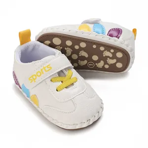 Dettaglio scarpe primi passi bianche per neonato con suola antiscivolo e macchie colorate