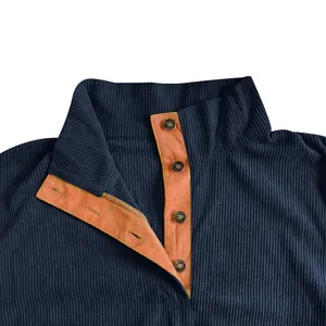 Primer plano del cuello de sudadera de pana azul marino con botones y forro naranja.