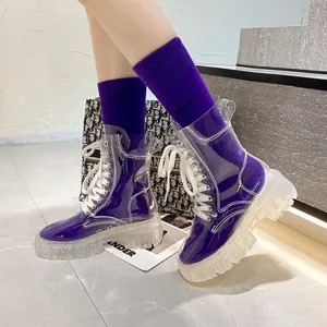 Detail view of transparent PVC lace-up boots paired with stylish purple socks in a studio setting