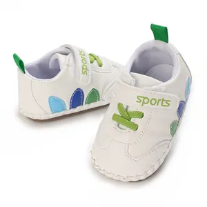 Primo piano di scarpine bianche per neonato con lacci verdi e cinturino sportivo velcro.