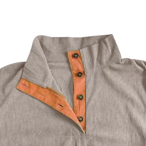 Detalle de sudadera de pana para hombre con cuello alto naranja y botones metálicos