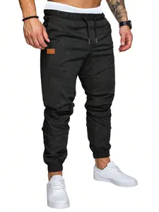 Detalle de pantalones cargo negros para hombre con cintura de cordón y parche de cuero