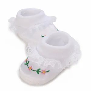 Detailansicht der weißen Baby-Prinzessin-Schuhe mit Blumenstickerei und Spitzenbesatz.