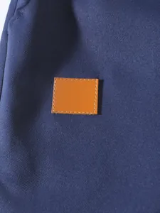 Primer plano de tela de sarga azul marino y parche de cuero naranja en pantalones cargo
