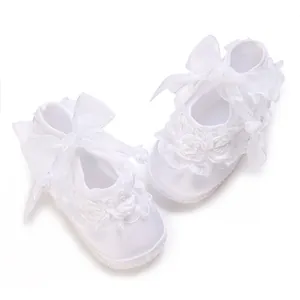 Close-up of white baby princess shoes featuring delicate lace flowers and satin bows