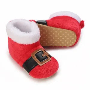 Detail van rode fluwelen babylaarzen met antislipzool en kerstmanontwerp voor baby's