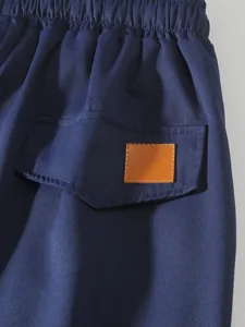 Primer plano de pantalones cargo azul marino con cintura elástica y parche de cuero