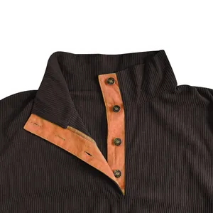 Detalle macro del cuello de la sudadera de pana con forro naranja y botones metálicos.