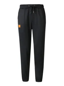 Detalle de pantalones deportivos negros para hombre con cordón y parche naranja.