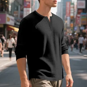 Detalle de camiseta Henley negra de manga larga con textura de gofre y tapeta