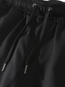 Detalle de pantalones cargo negros con cintura elástica y cordones con puntas metálicas