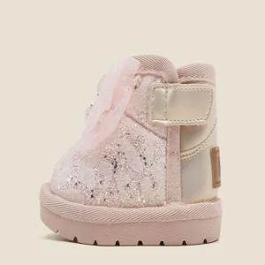 Detailed view of sparkly pink baby girl snow boots featuring a delicate lace bow accent.