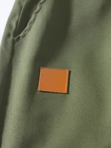 Primer plano de pantalones cargo verde oliva con detalle de parche de cuero marrón.
