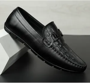 Nahaufnahme schwarzer Leder-Loafer mit Krokoprägung und metallischem Schnallendetail.