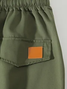 Detalle de pantalones cargo verde oliva con cintura elástica y parche de cuero.