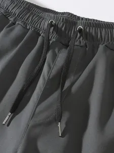 Vista detallada de la cintura elástica y los cordones negros en pantalones cargo gris oscuro
