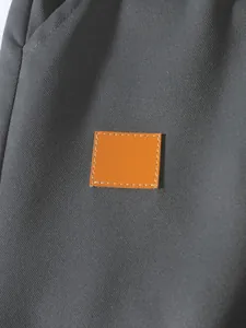 Detalle macro de la tela gris oscuro y el parche de cuero naranja en pantalones cargo