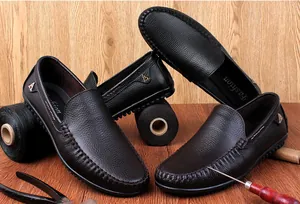 Klassische Herren-Slipper aus Leder mit traditionellen Werkzeugen auf Holzgrund
