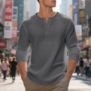 Detalle de la textura de punto gofrado y el cuello abotonado en la camiseta Henley gris