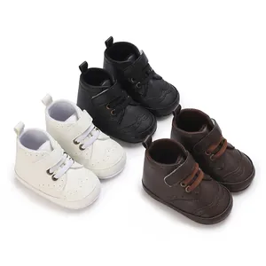 Bottines pour bébé en blanc, noir et marron avec semelles souples antidérapantes.